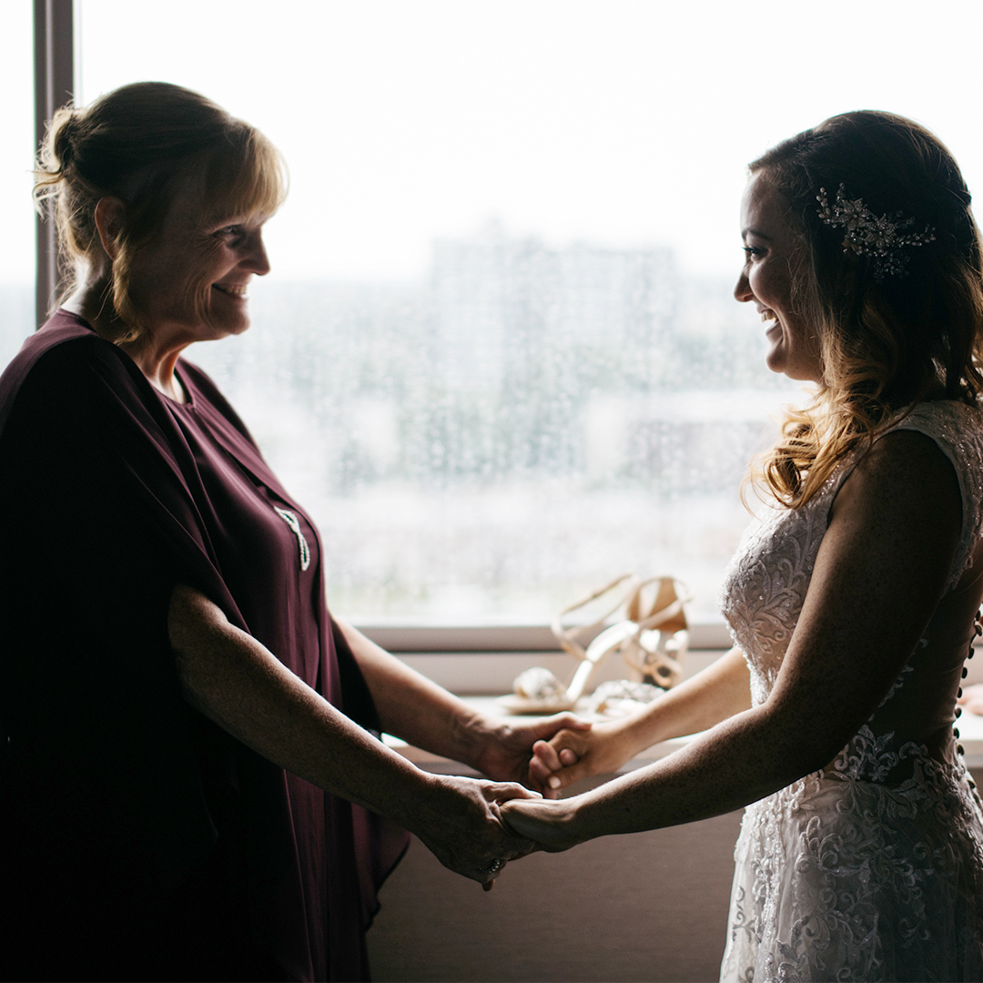 Smiling Mom and daughter holding hands on wedding day