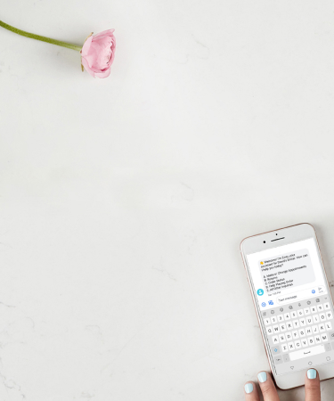 hand scrolling on a cell phone on a table with a rose